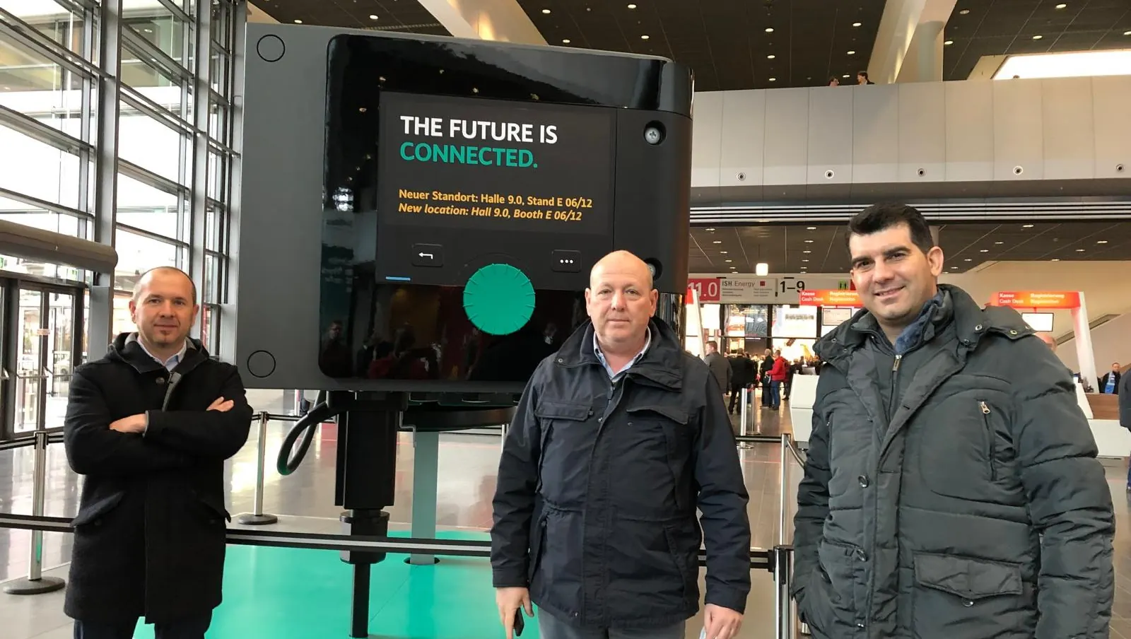 Tre rappresentanti di Hydrosolution in fiera davanti allo schermo «The future is connected»